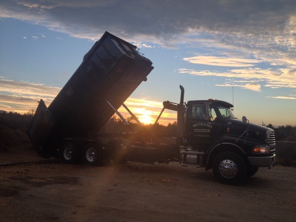 Dump truck with raised bed at sunset on a dirt lot