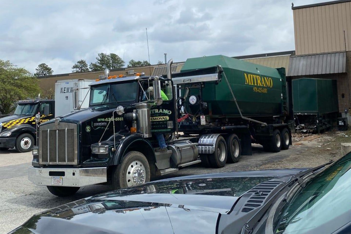 Black truck and green dumpster trailer in a parking lot