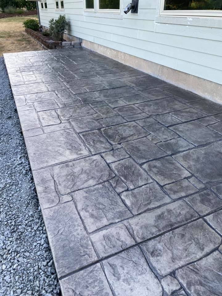 Newly poured concrete patio next to a brown house with a door and windows.