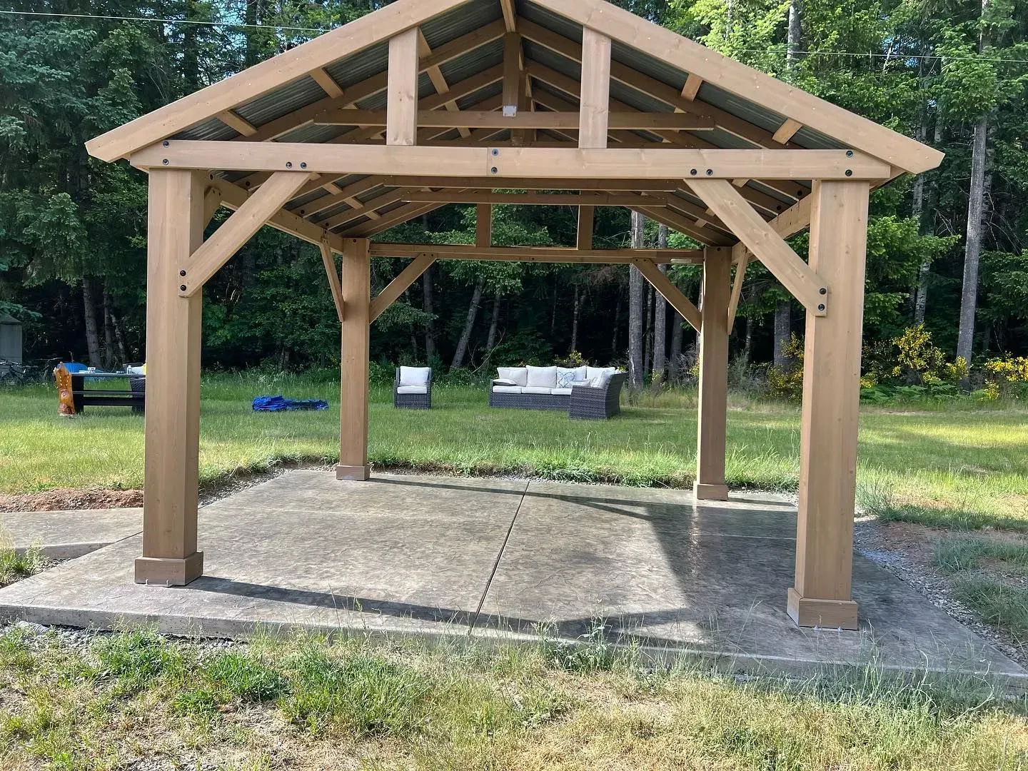 Wooden gazebo on a concrete pad, with outdoor seating visible in the background.