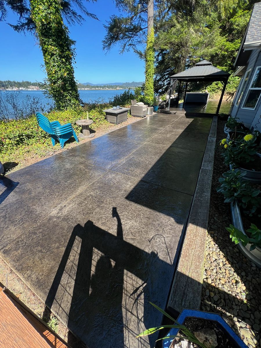Patio with water view, blue chair, and gazebo. Sunlight creates long shadows.