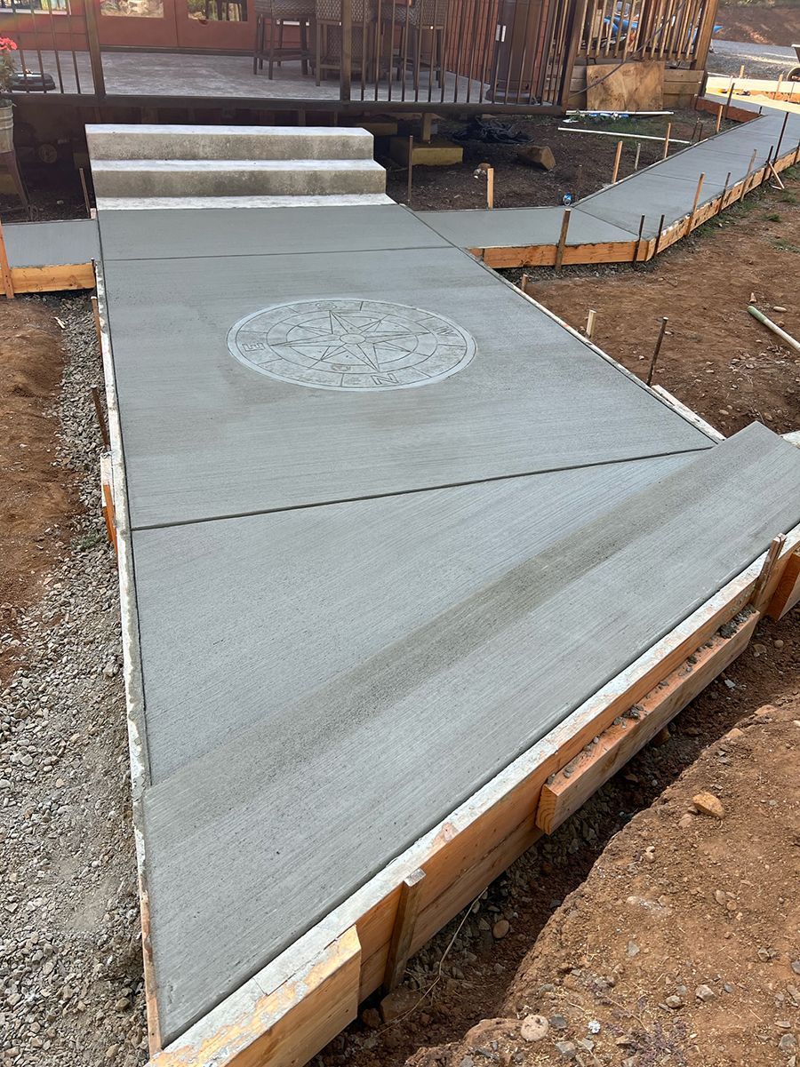 New concrete ramp and stairs under construction, with wooden forms and decorative emblem in the walkway.