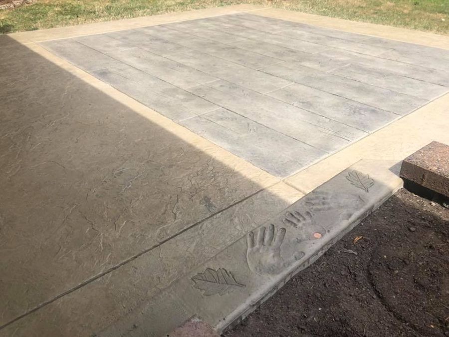 Concrete patio with stamped wood grain pattern and handprints; a border of plain concrete.