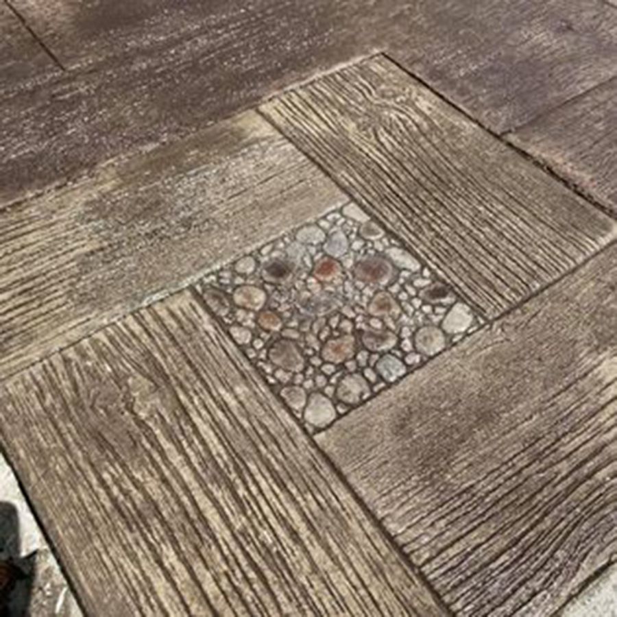 Stamped concrete patio with wood grain pattern and a central square of pebbles.