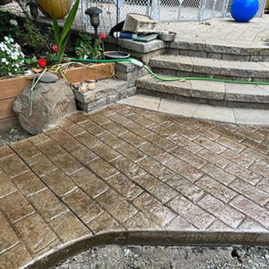 Stamped concrete patio with brick pattern, steps, and garden.