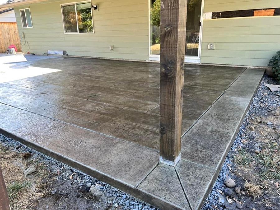 Newly poured concrete patio with wood grain texture, next to a wooden support post.