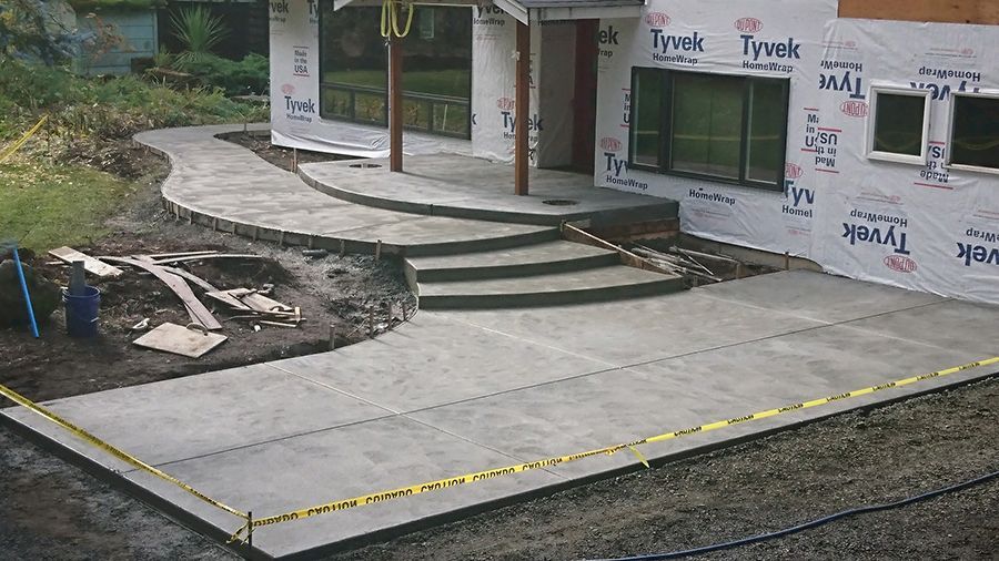 Concrete walkway and steps leading to a house under construction; caution tape present.