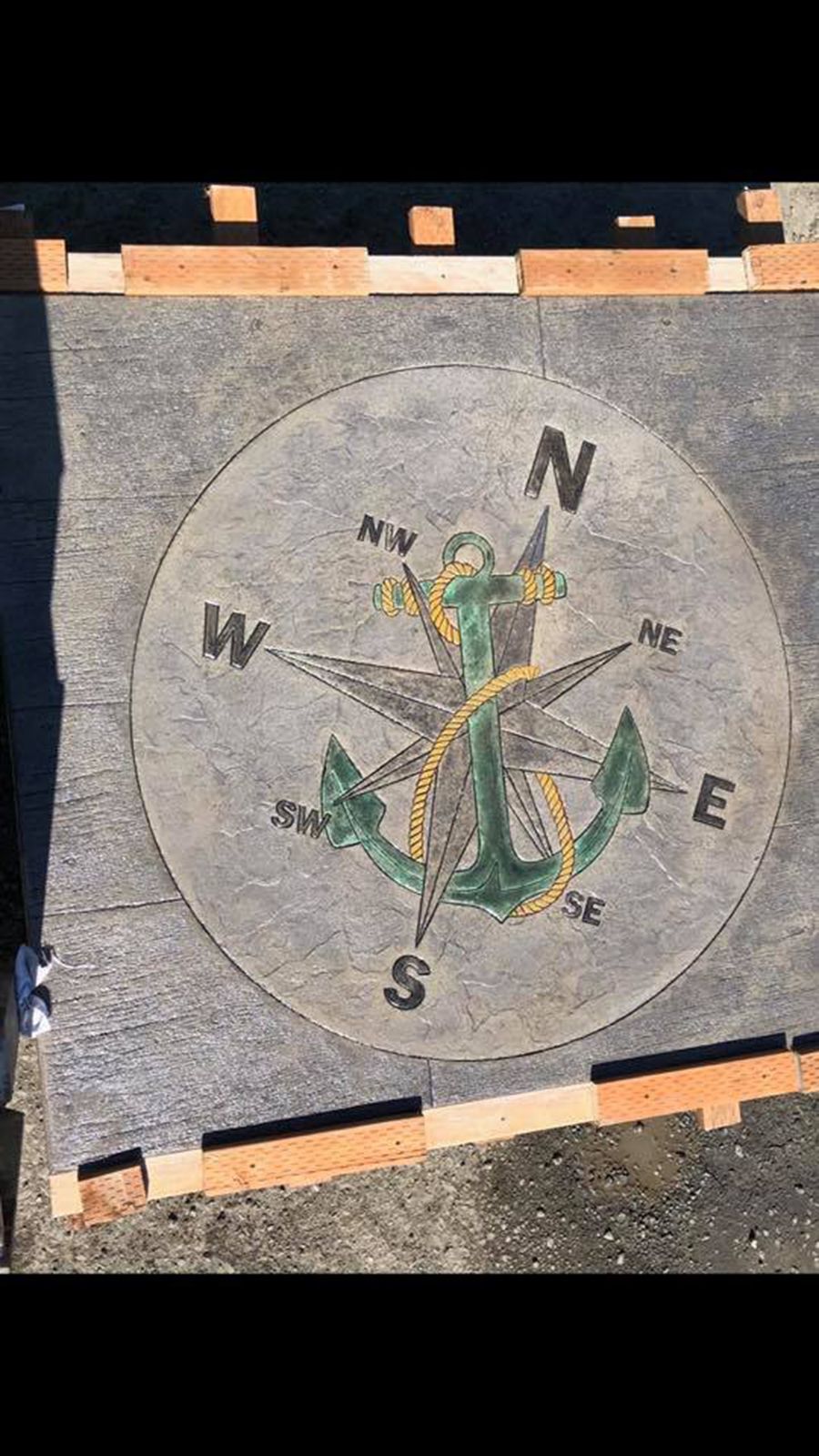 Concrete patio with a compass rose and anchor design, colored green, gold, and black.