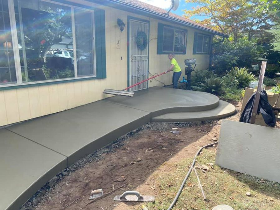 Worker smoothing wet concrete on a residential pathway and steps.