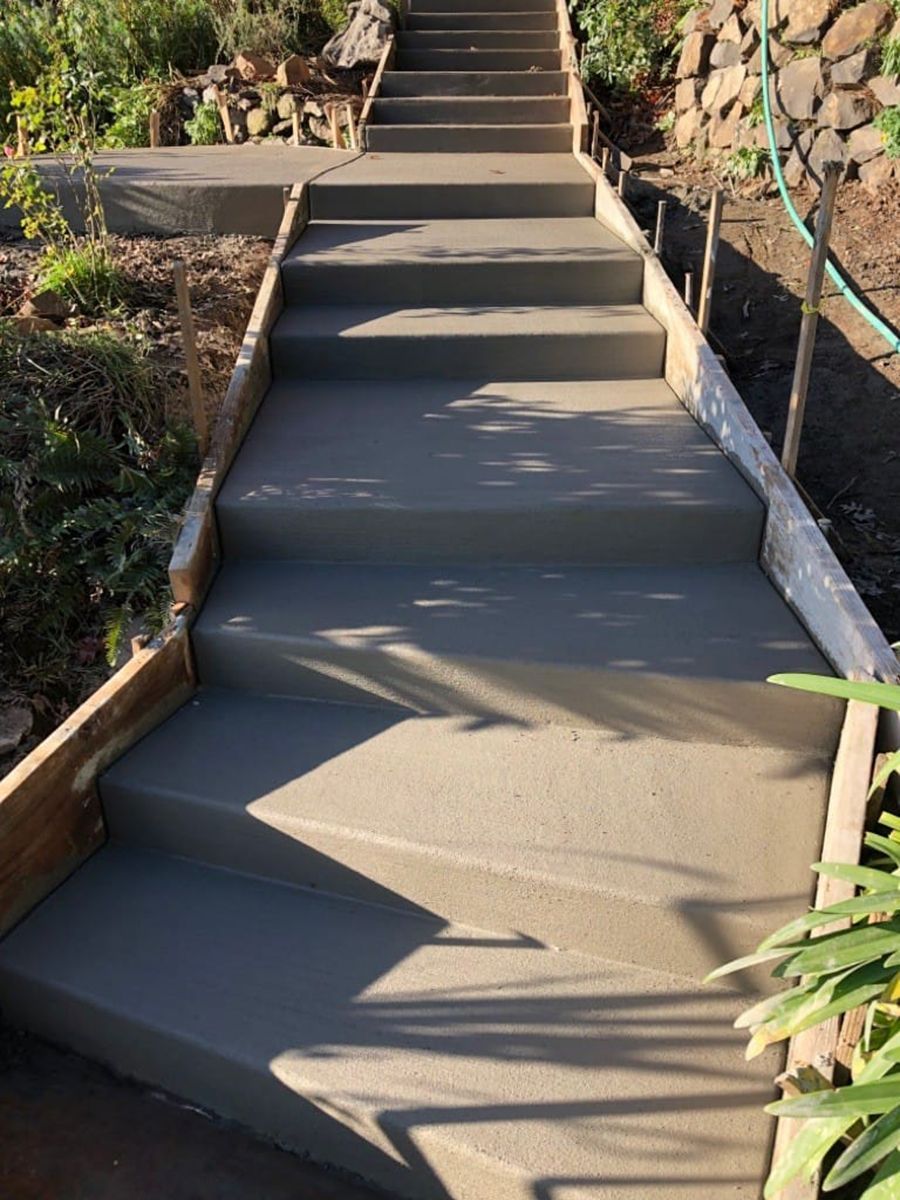 Concrete stairway leading uphill between wooden side forms in an outdoor setting.