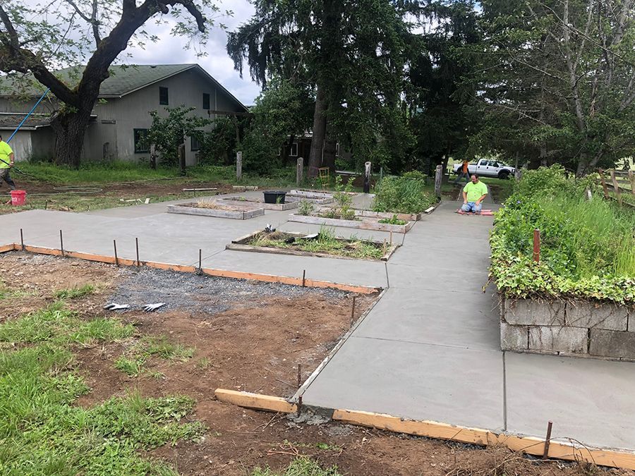 Concrete pathway and garden beds under construction with workers.