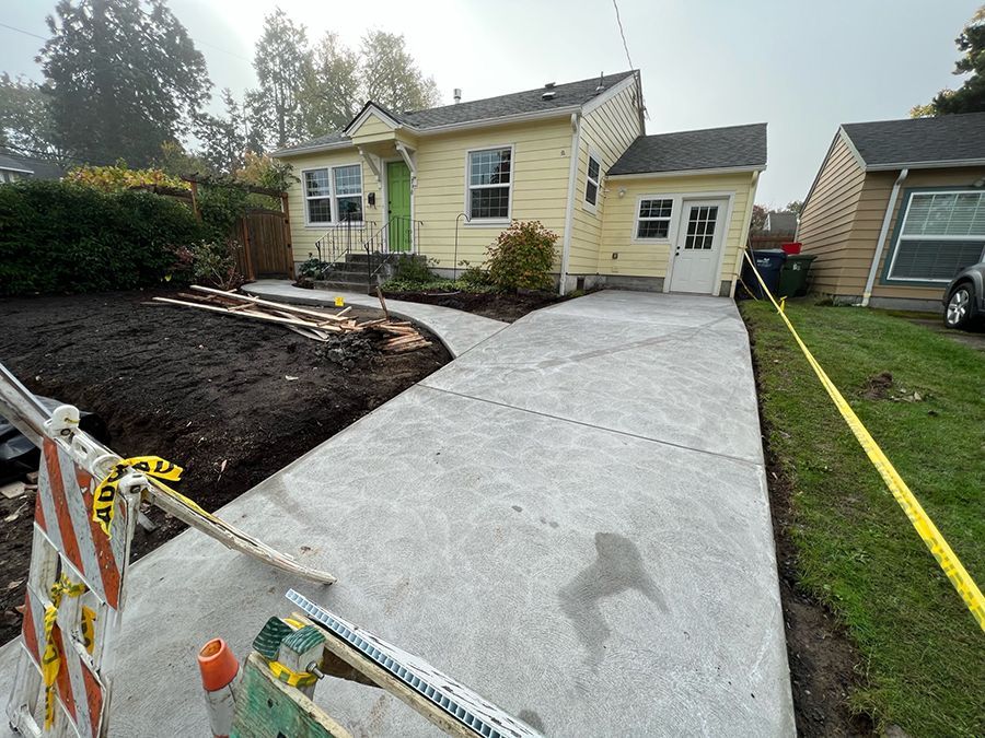 A yellow house with new concrete walkway. Brown mulch and caution tape in the yard.
