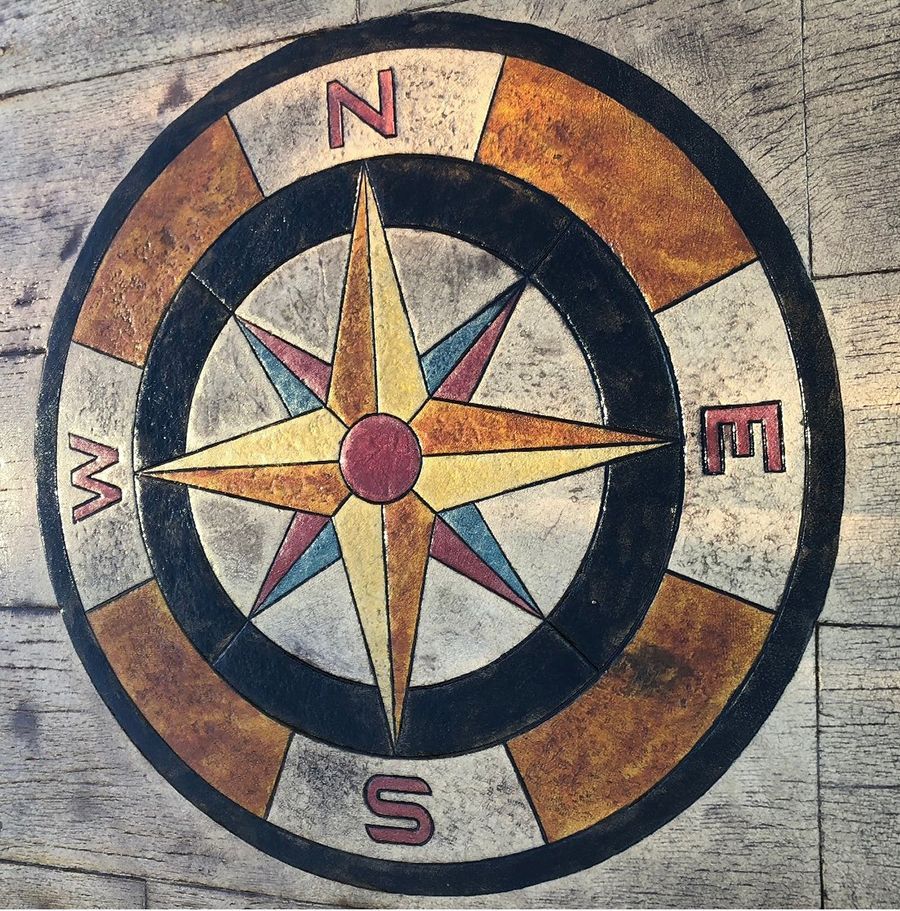 Compass rose embedded in a concrete surface; shows north, south, east, and west directions.