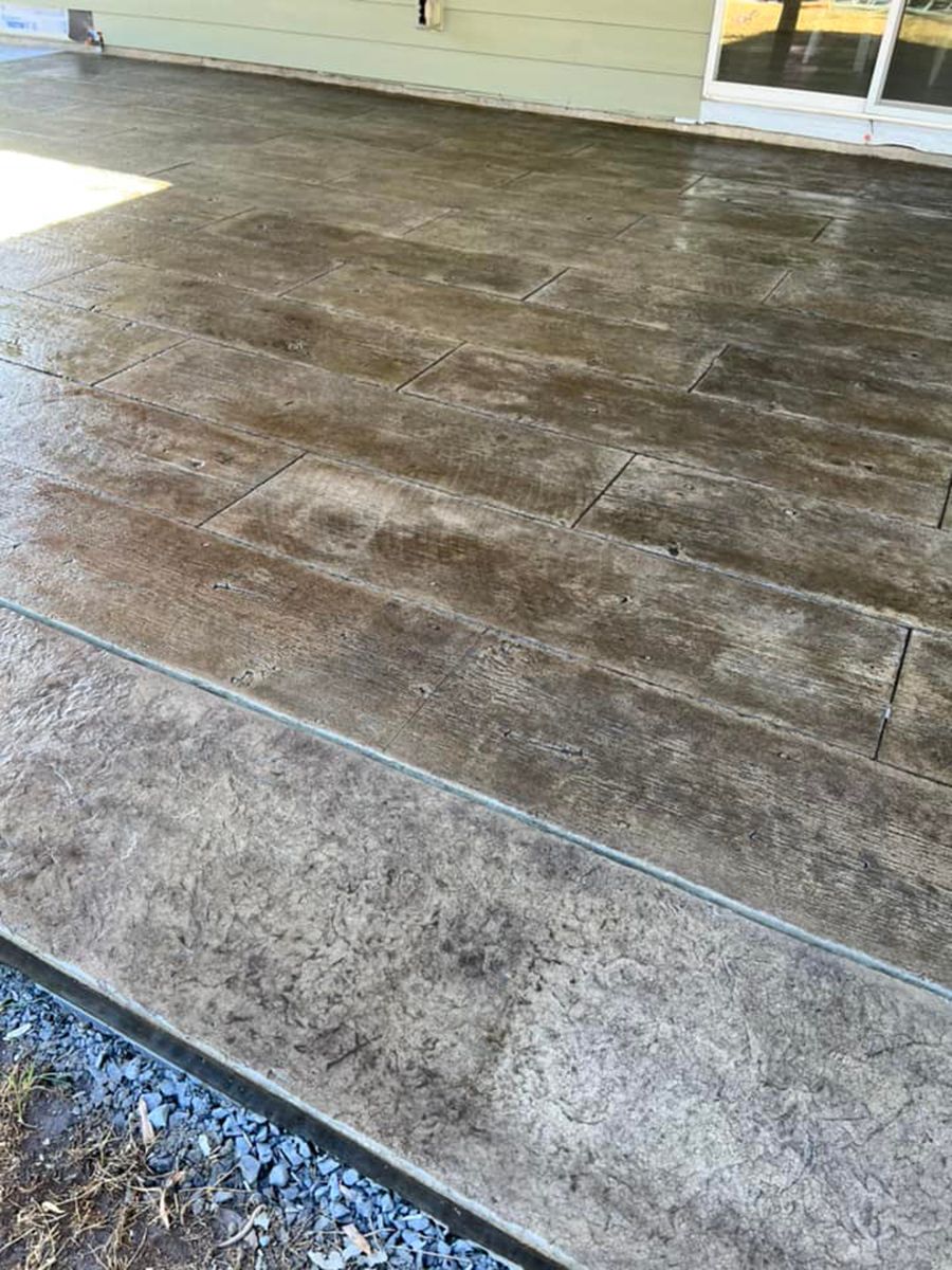 Stamped concrete patio with wood-plank design, various shades of brown and gray.