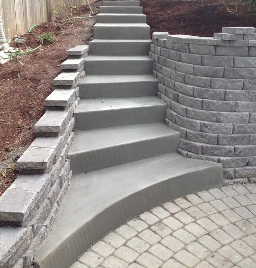Concrete steps with retaining walls, leading up a sloped yard.