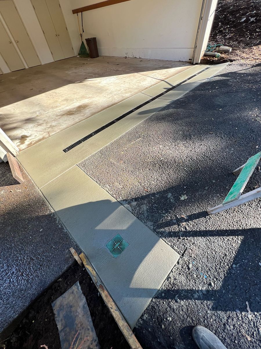 New concrete walkway with a drainage channel next to a garage entrance.