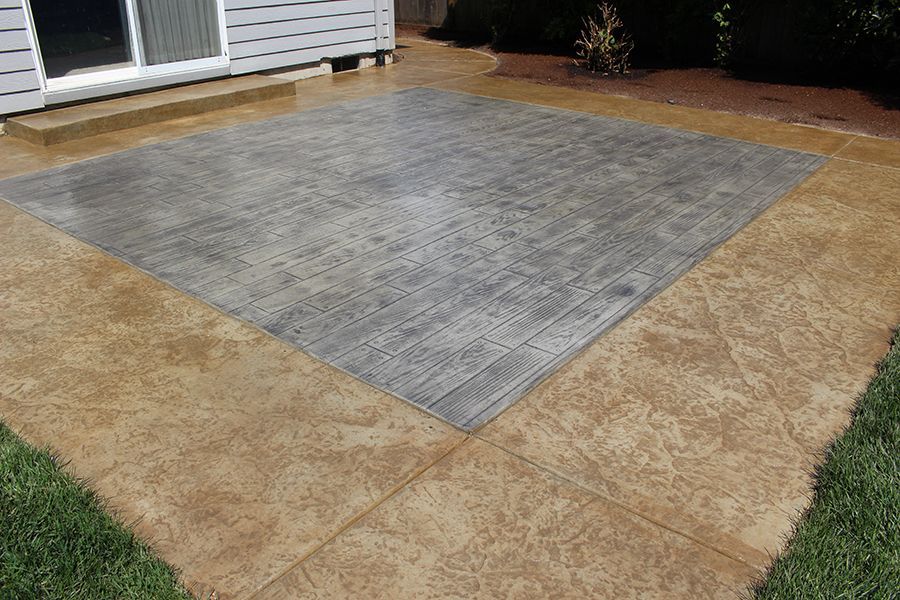 Concrete patio with gray center, brown border, and surrounding grass.