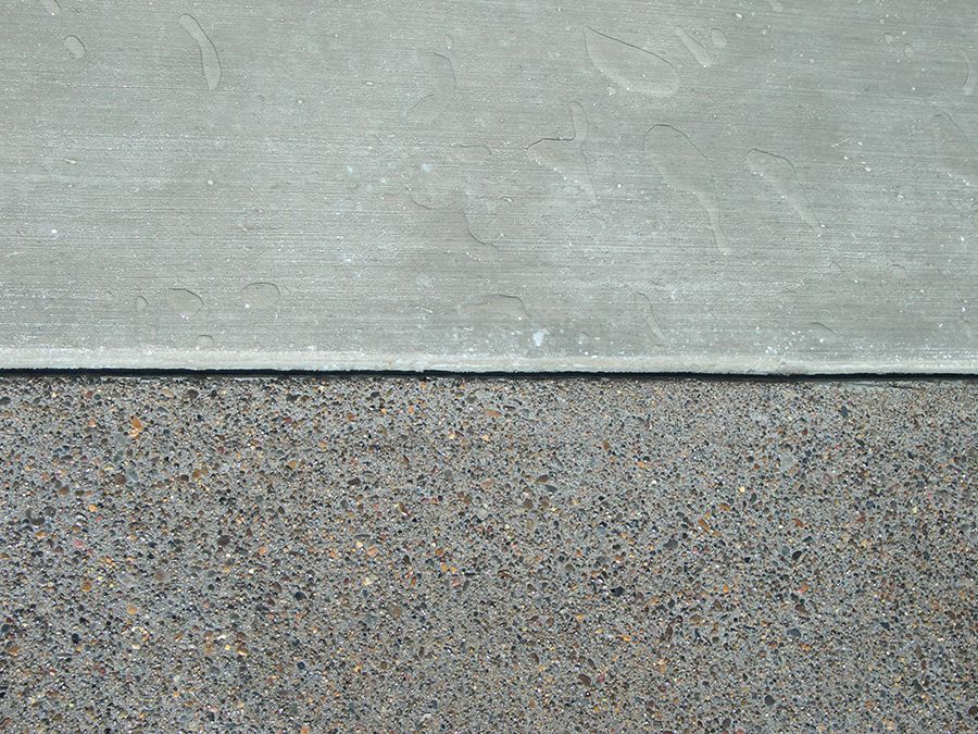 Gray concrete sidewalk meets asphalt pavement.
