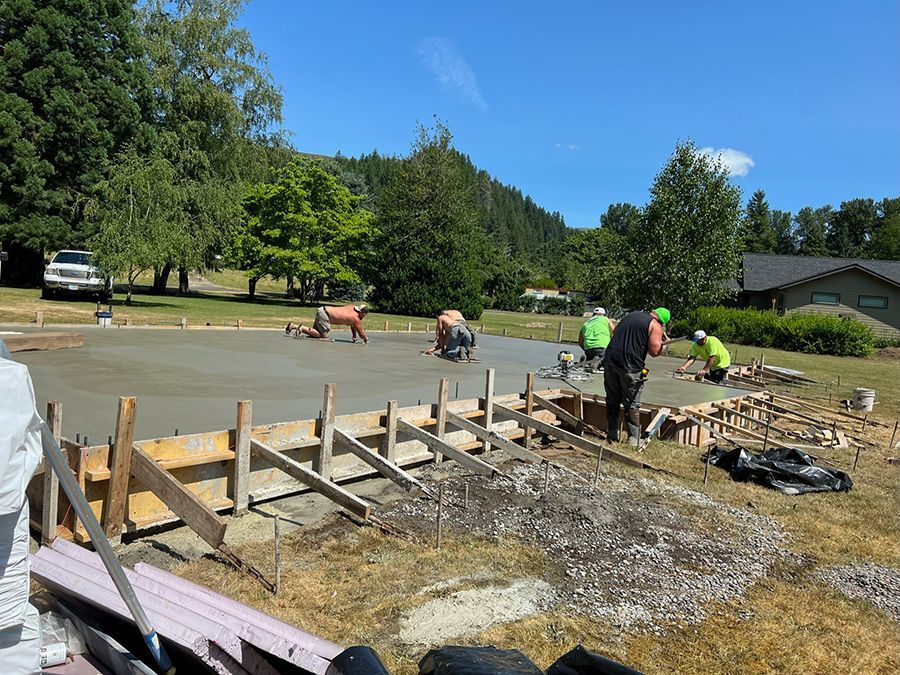 Concrete being poured for a driveway, workers in progress on a sunny day.