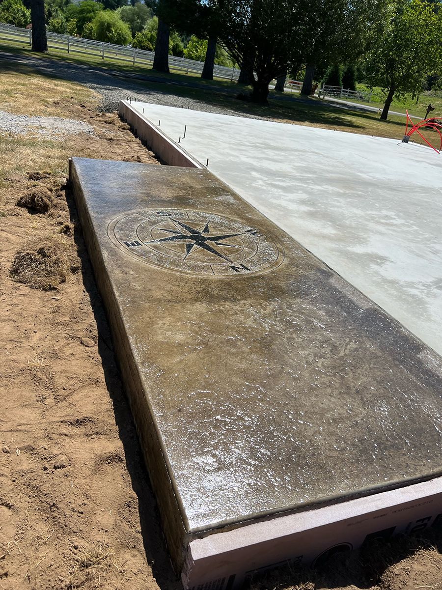 Concrete slab with compass rose design, bordered by pink insulation. Construction site, outdoor.