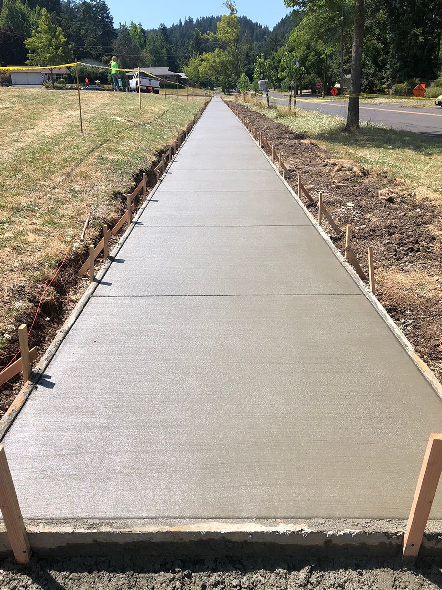 Newly poured concrete sidewalk with wooden forms, in a grassy setting.