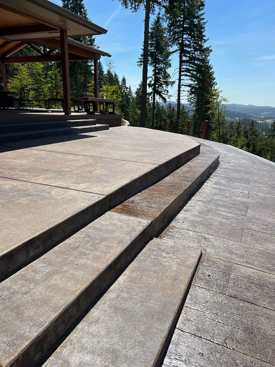Concrete steps leading to a wooden shelter with a scenic hilltop view. Sunny day, blue sky.