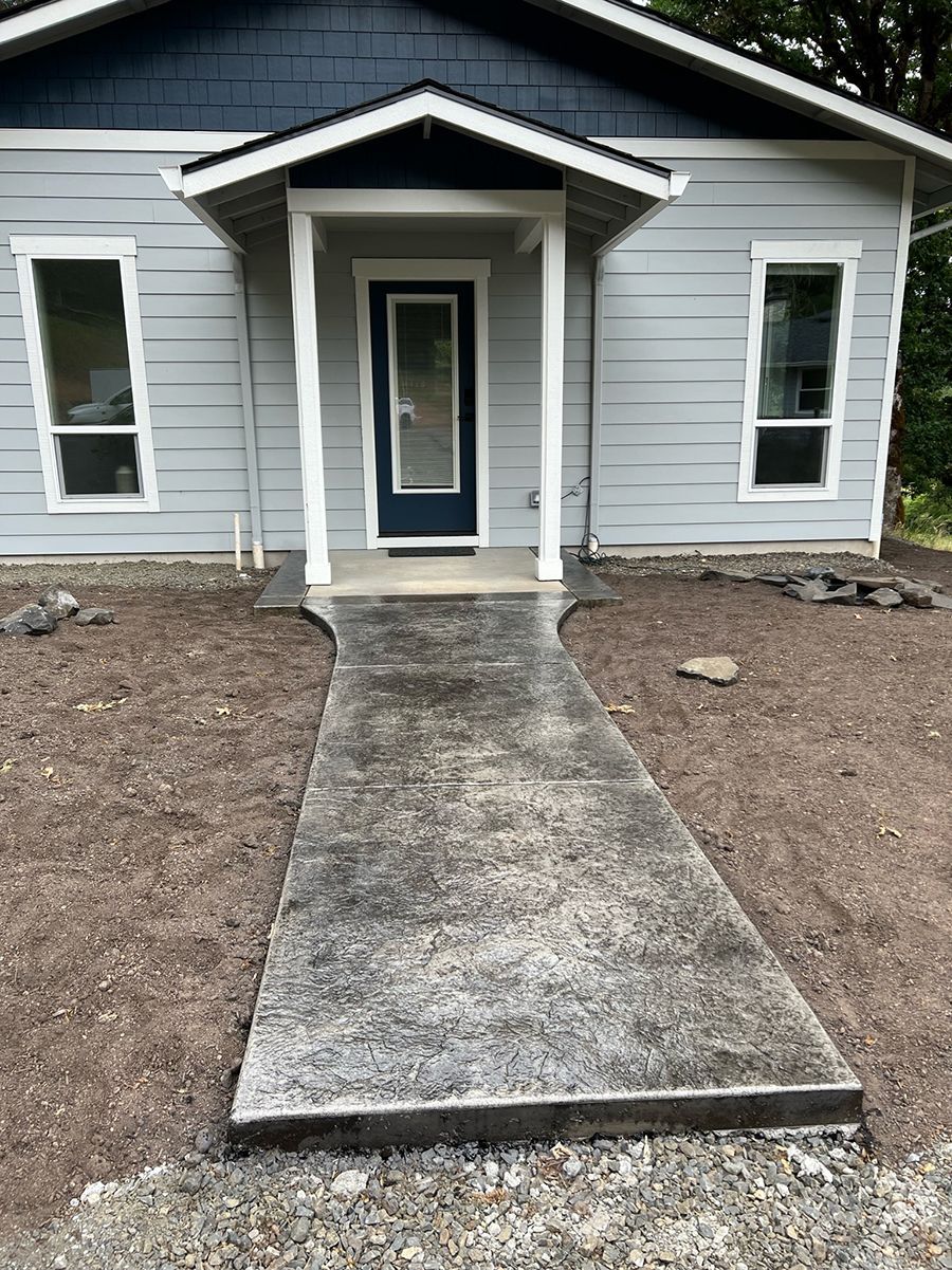 Gray house with a concrete walkway leading to the front door.
