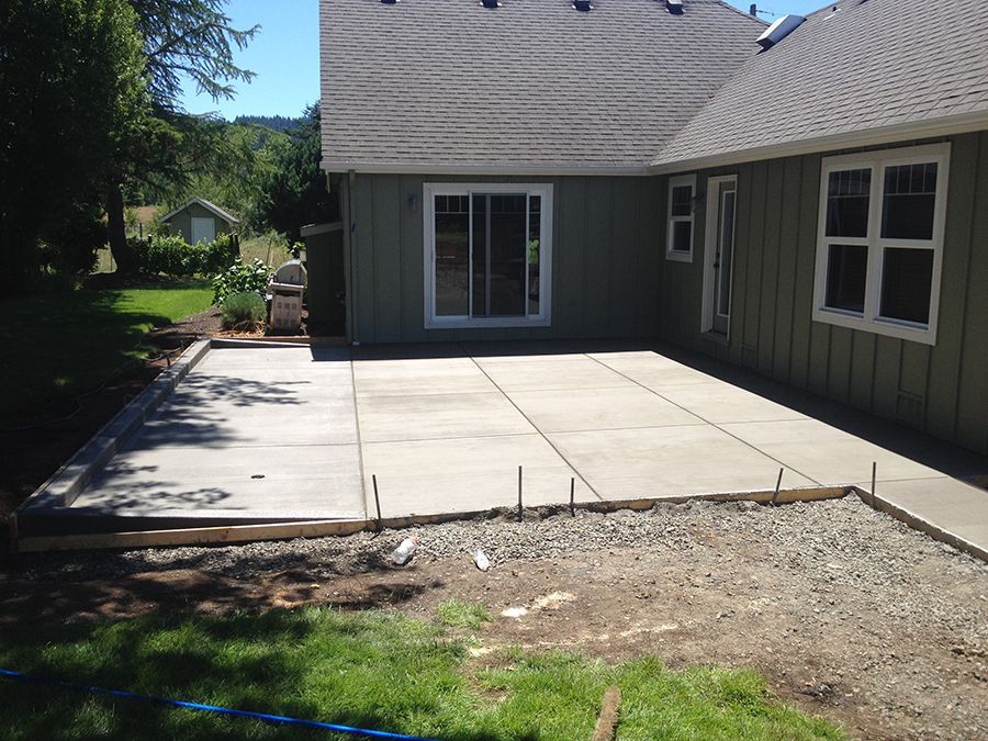 A newly poured concrete patio next to a house with a sliding glass door.