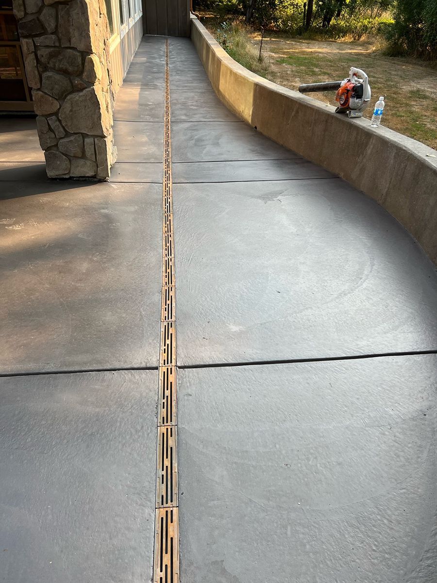 Gray concrete ramp with a drain, leading toward a building entrance.