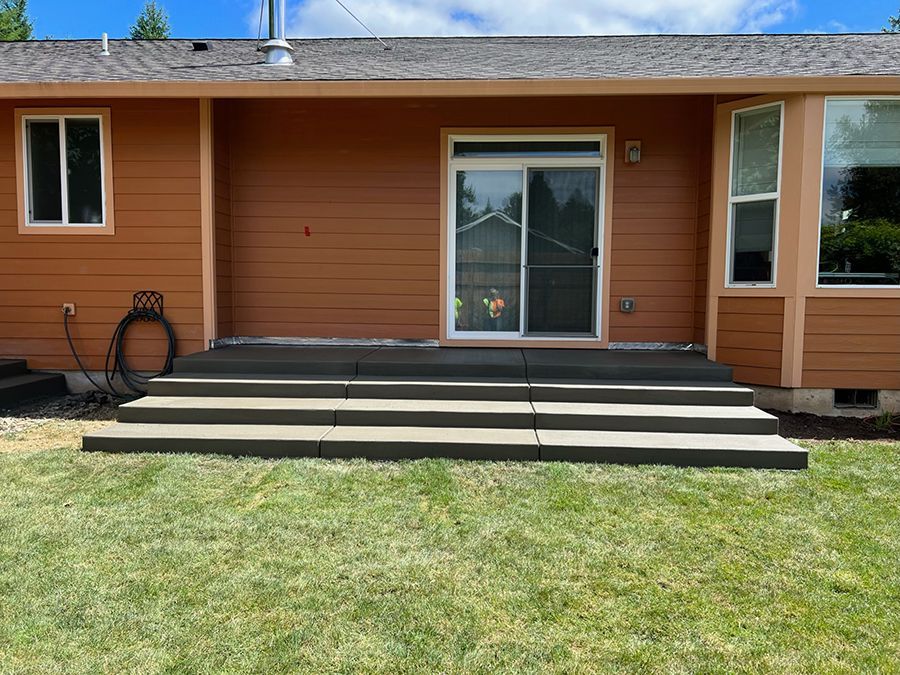 Brown house exterior with three gray concrete steps leading to a sliding glass door.