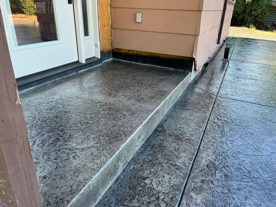 Concrete porch with stamped texture and step leading to a doorway; exterior.