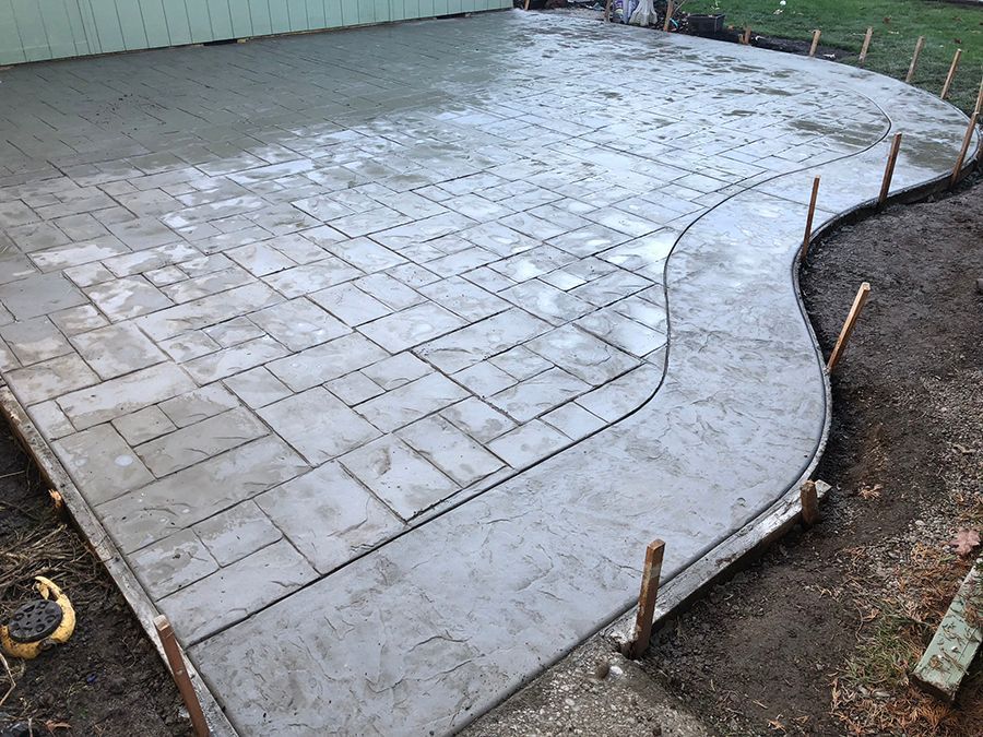 Freshly poured concrete patio with patterned design and curved walkway.