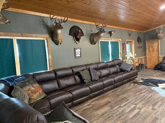 Large brown leather sectional sofa in a room with taxidermied animals mounted on green and wood-paneled walls.