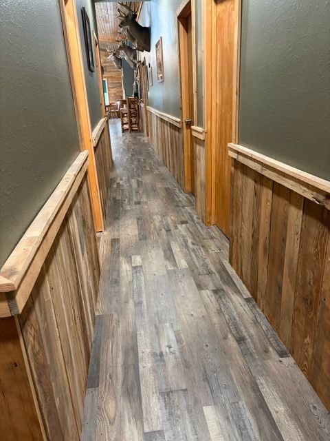 Narrow hallway with wood paneling, wood floor, and olive green walls. Doors on right side.