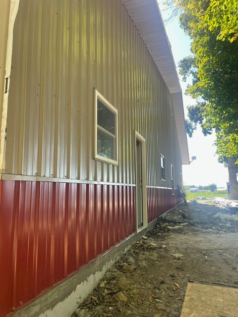 Red and silver metal building with white trim, a small window, and a door.