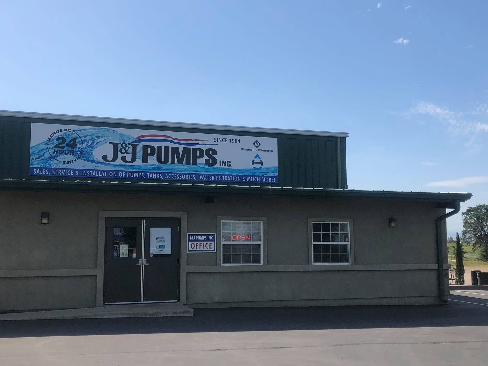 J&I Pumps storefront with blue sign, gray building, and glass entrance under a clear sky