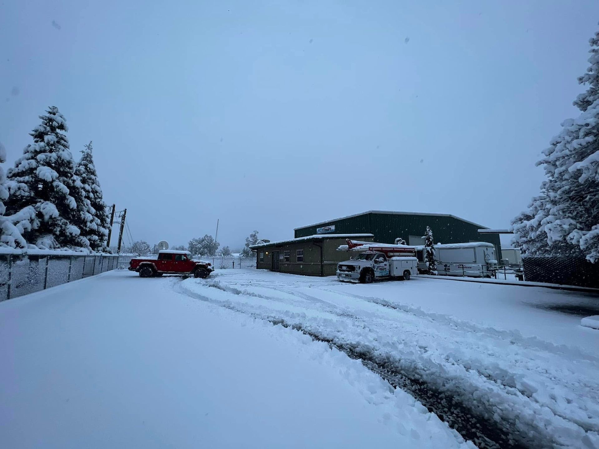 Snow-covered parking lot with parked cars and a building under a cloudy winter sky