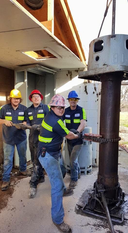 Crew in hard hats operating a large construction drill beside a building