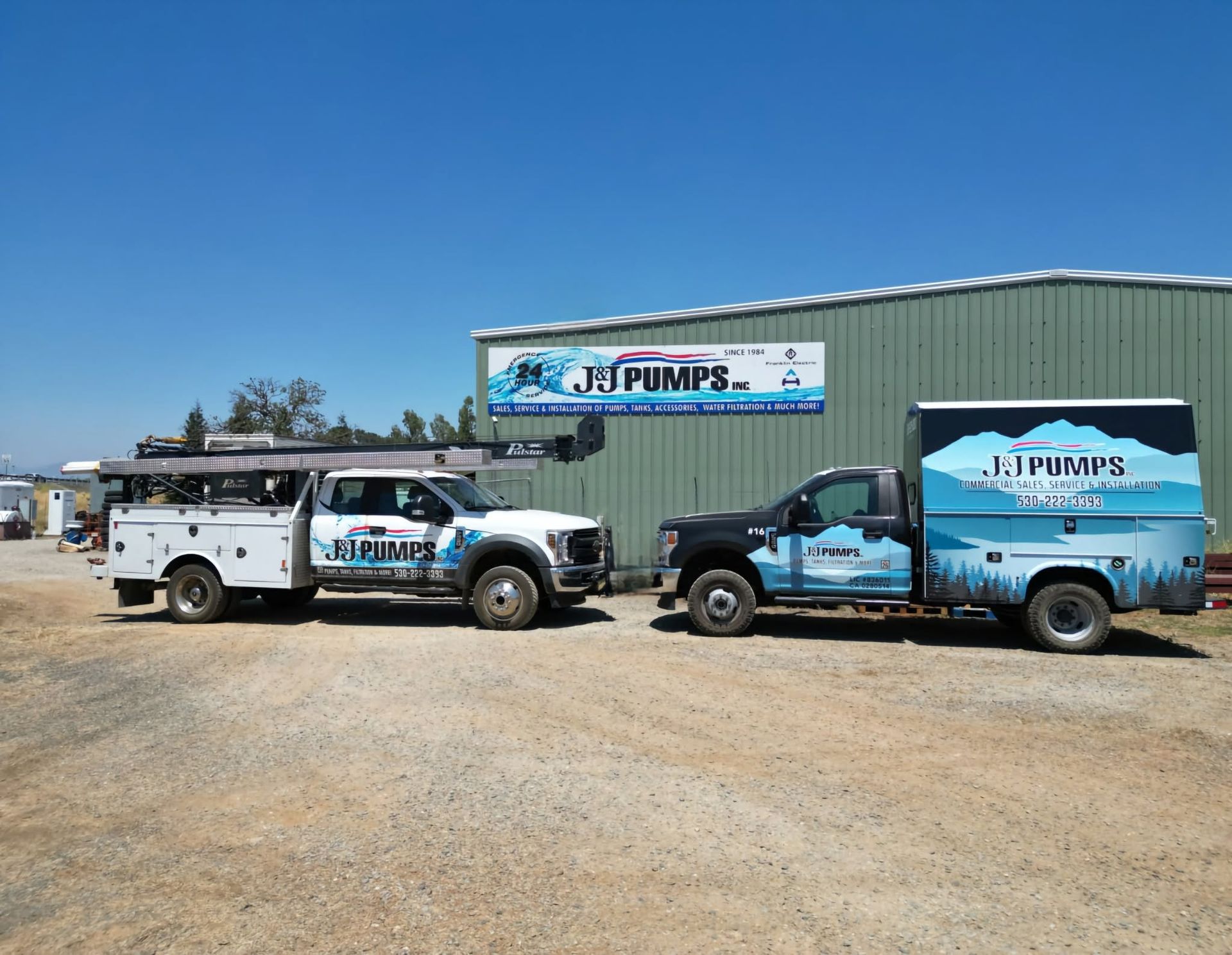 Two work trucks parked outside a pump service building under a clear blue sky.