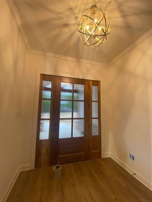 A front entryway with wood flooring, light-colored walls, a wooden door with glass panels, and an orb-shaped light fixture.