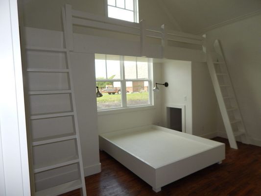 A white platform bed sits beneath a loft area with two white ladders in a minimalist bedroom with dark wood floors.