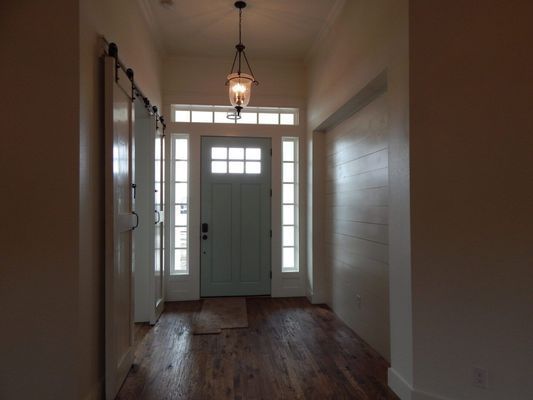 Entryway with hardwood floors, a light blue front door, sidelight windows, and a hanging pendant light fixture.