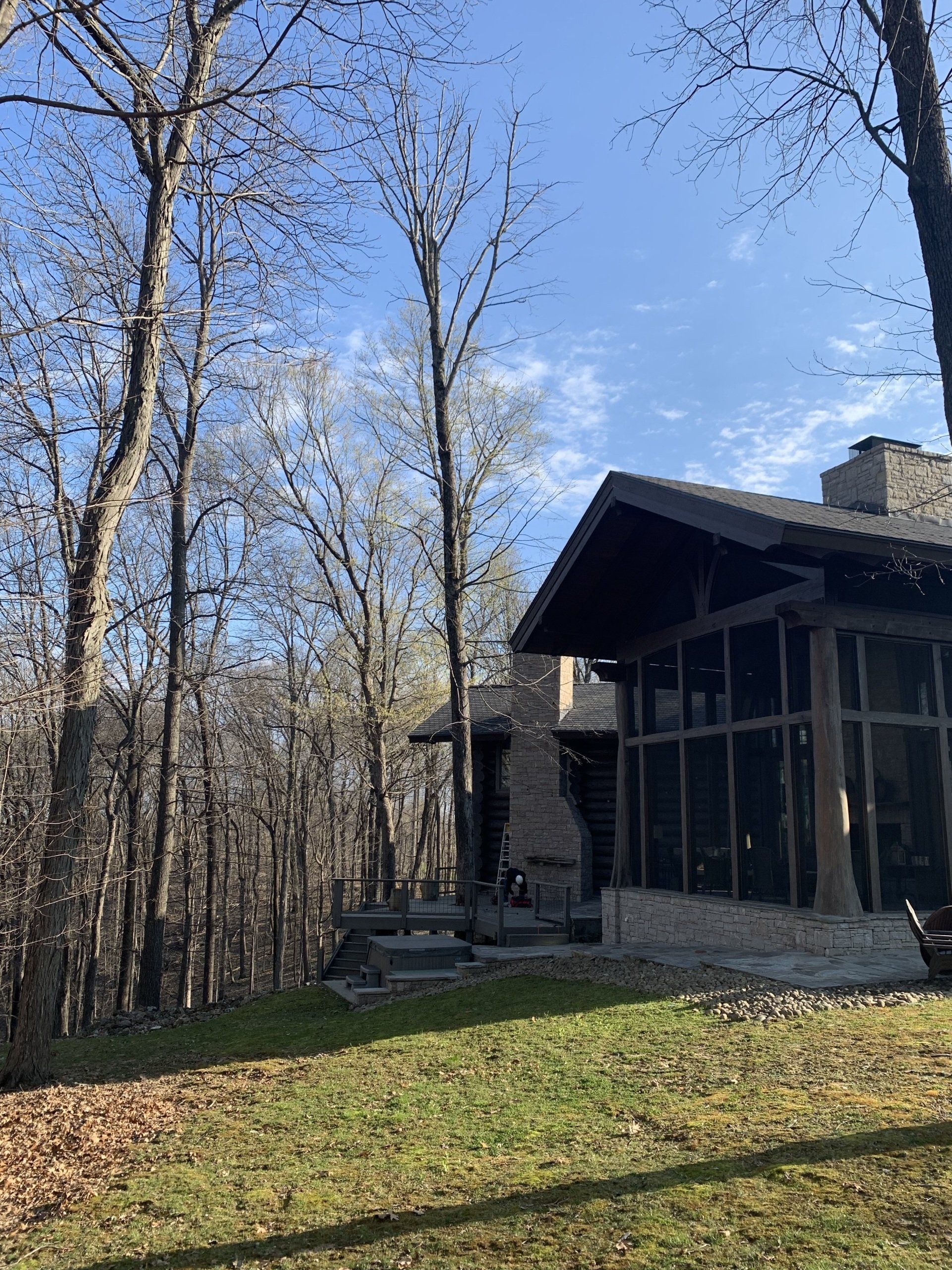 A house with a screened in porch in the middle of a forest.