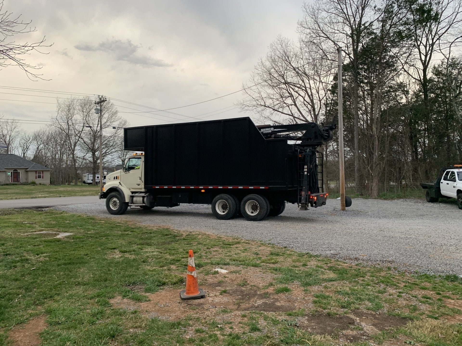 A dump truck is parked on the side of the road in a grassy field.