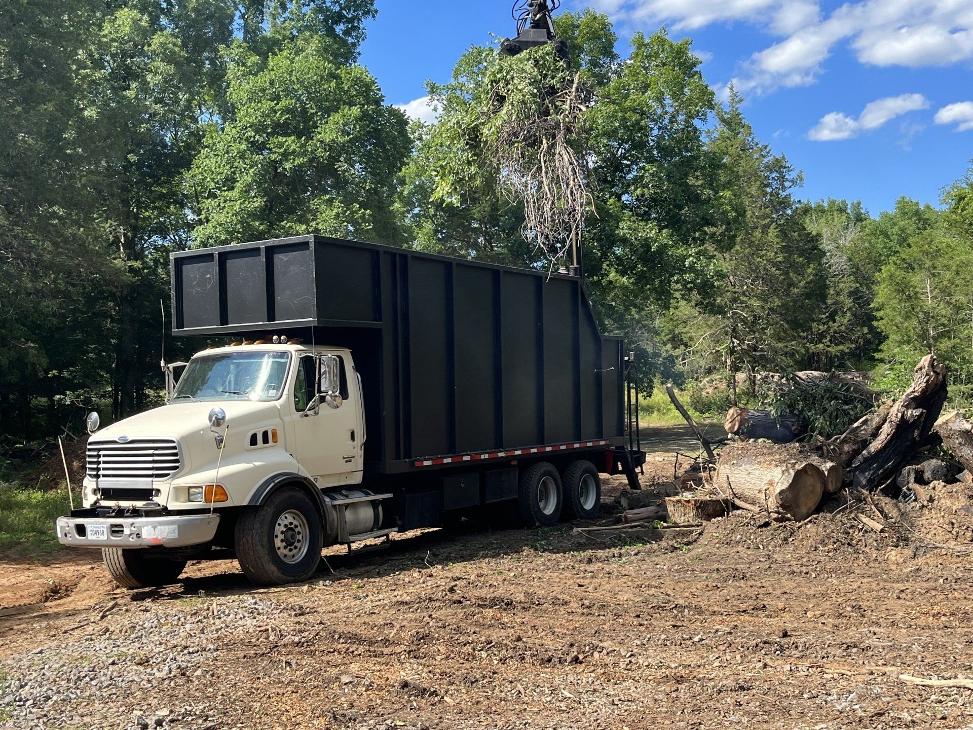 A white dump truck is parked in a dirt field.