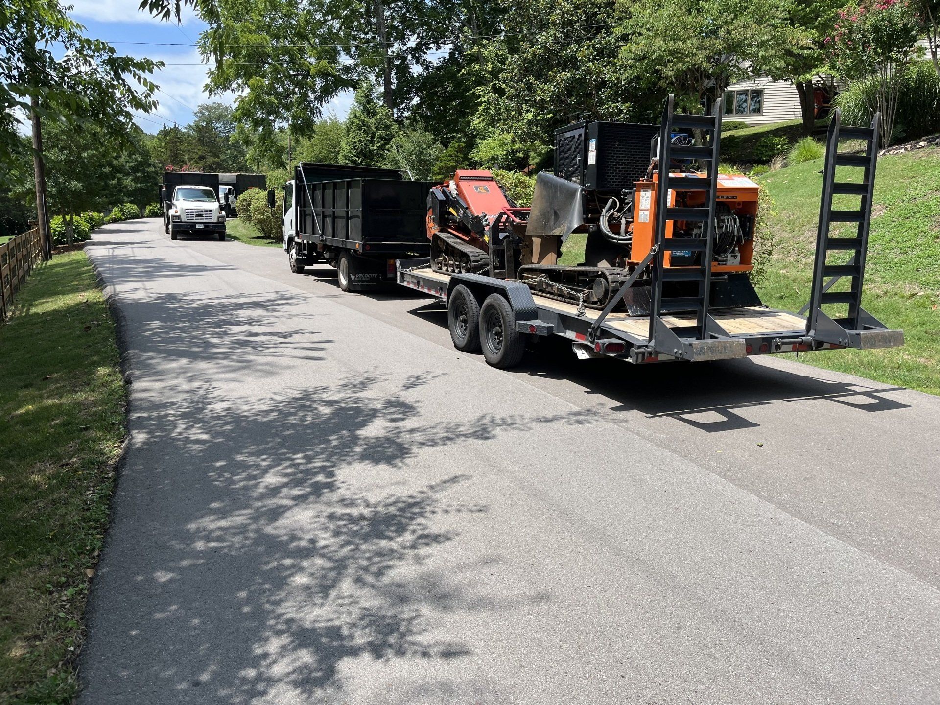 A trailer with a machine on it is parked on the side of a road.