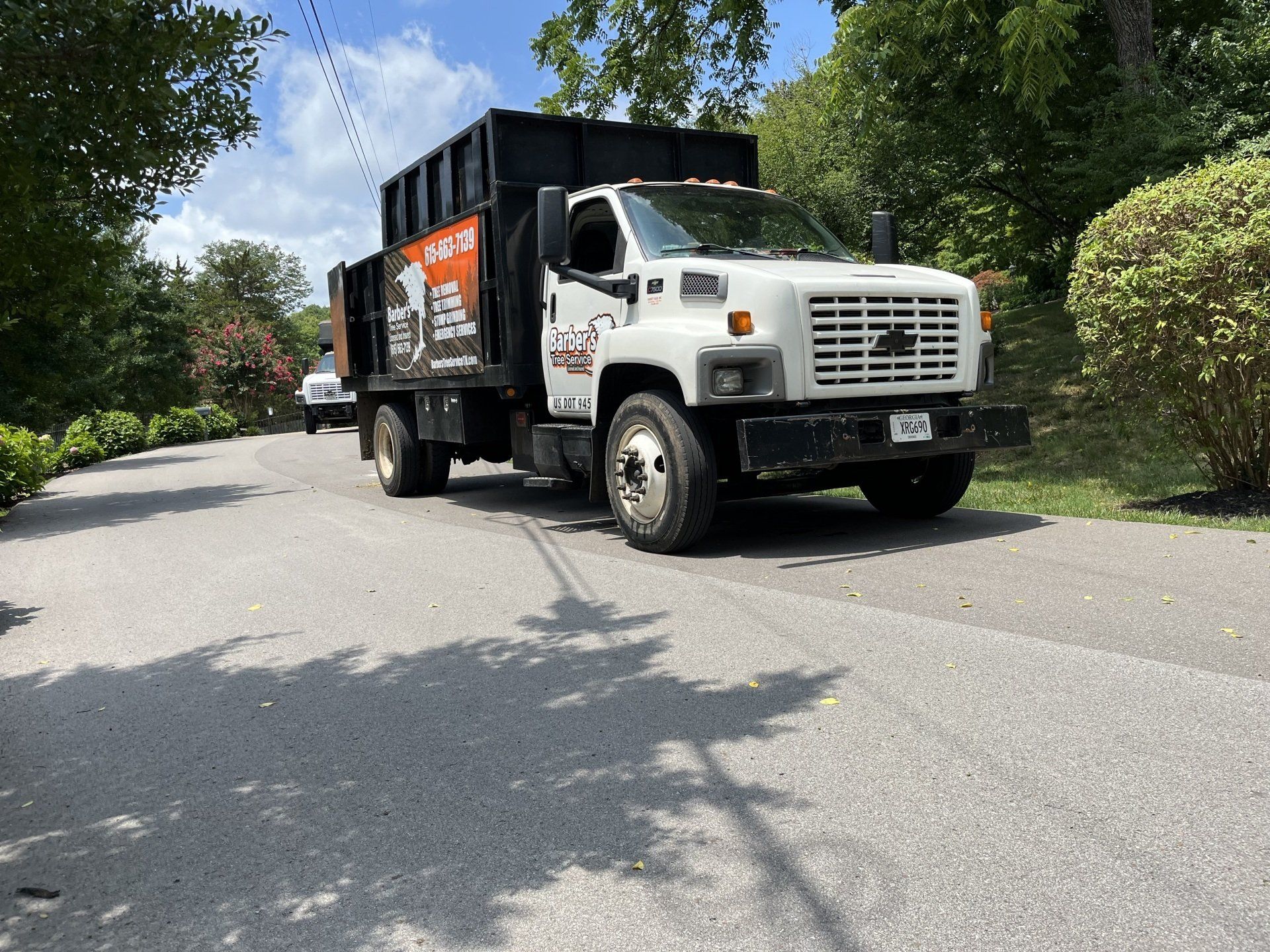 A dump truck is driving down a road with trees in the background.