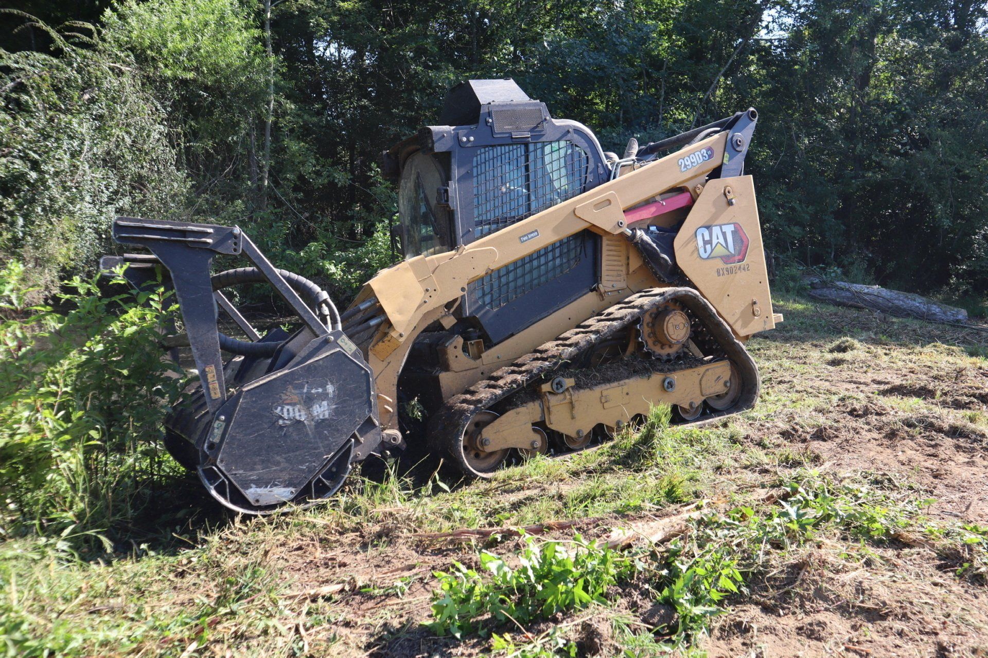 A cat tractor is cutting grass in a field.