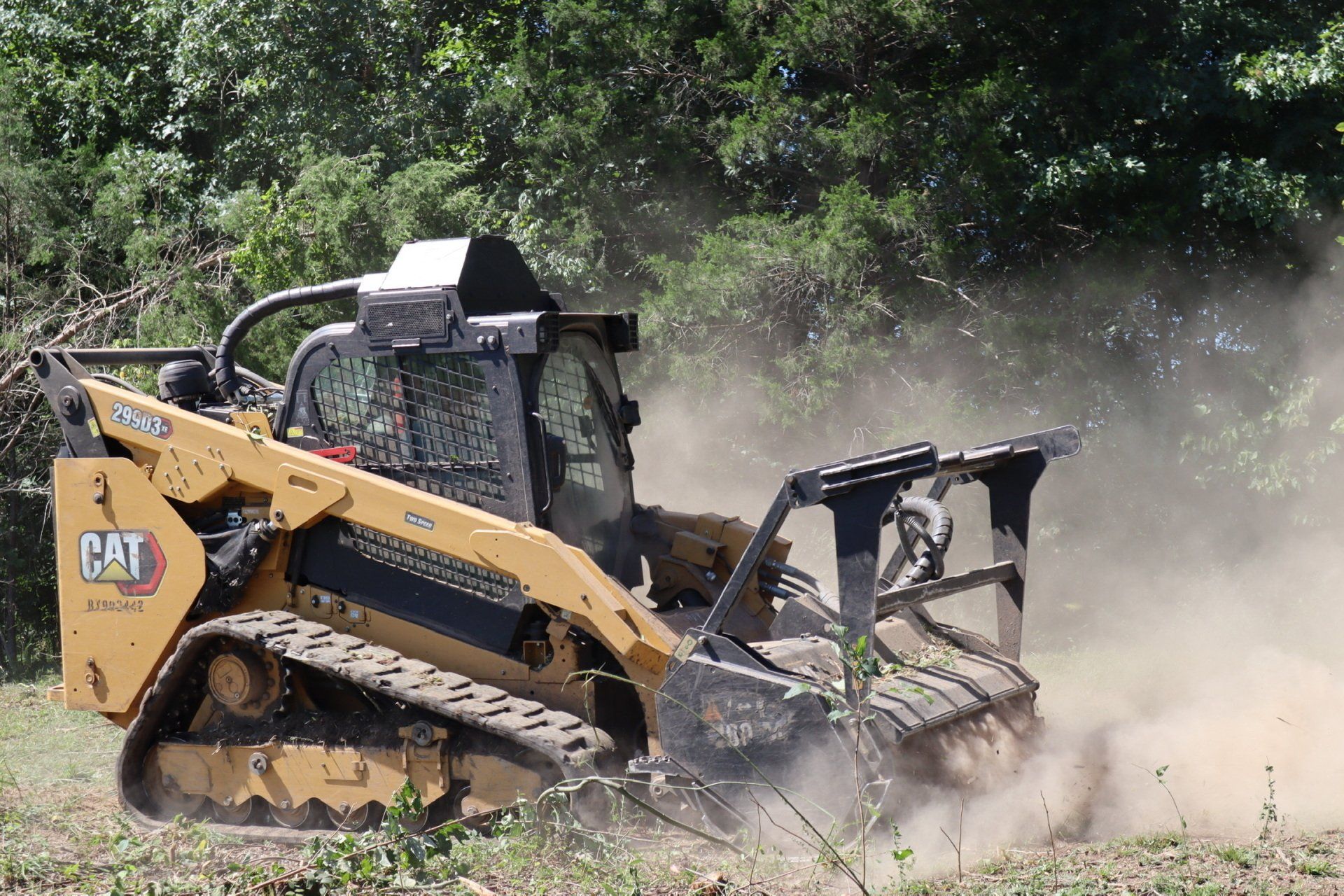 A yellow and black cat tractor is driving through a field.