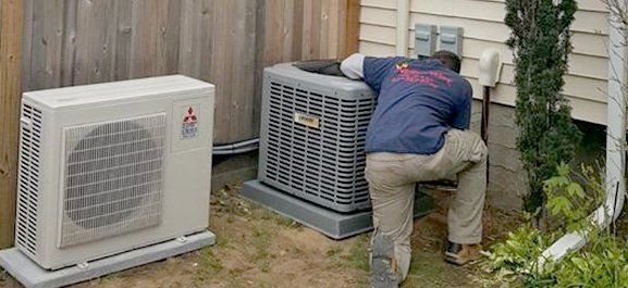 A man is working on an air conditioner outside of a house.